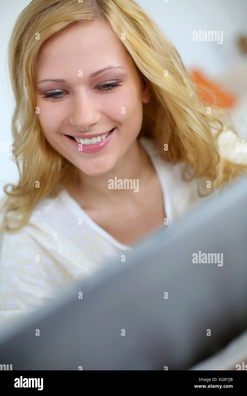 Blond girl sitting in sofa with digital tablet Stock Photo - Alamy