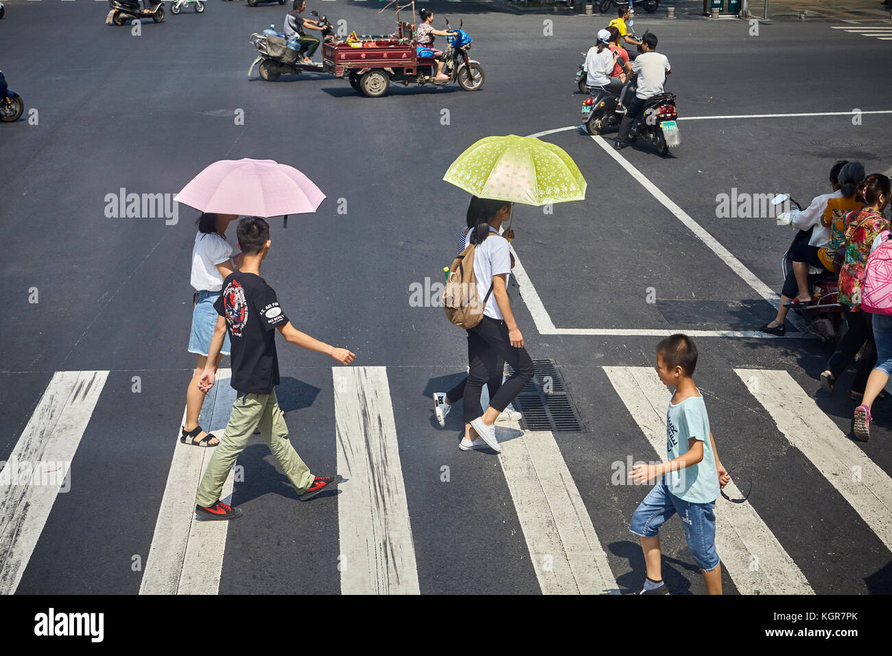 Guilin, China - September 15, 2017: Women with sun umbrellas cross street in downtown Guilin. Stock Photo