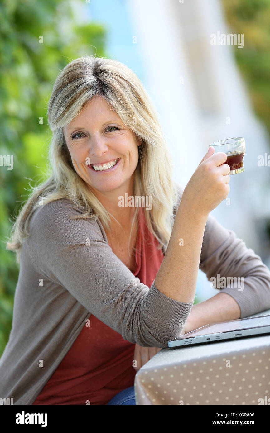 Mature woman relaxing with tablet and coffee in garden Stock Photo - Alamy