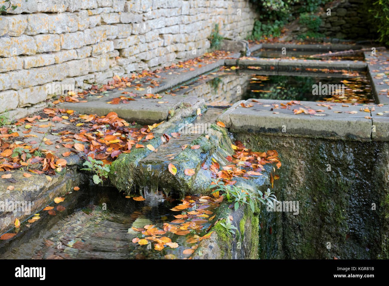 Stone water troughs covered in autumn leaves in Bisley, Cotswolds, Gloucestershire, England Stock Photo
