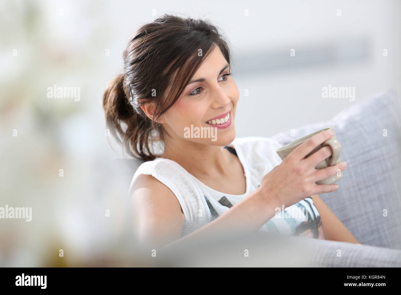 Young woman relaxing in sofa with cup of hot drink Stock Photo - Alamy