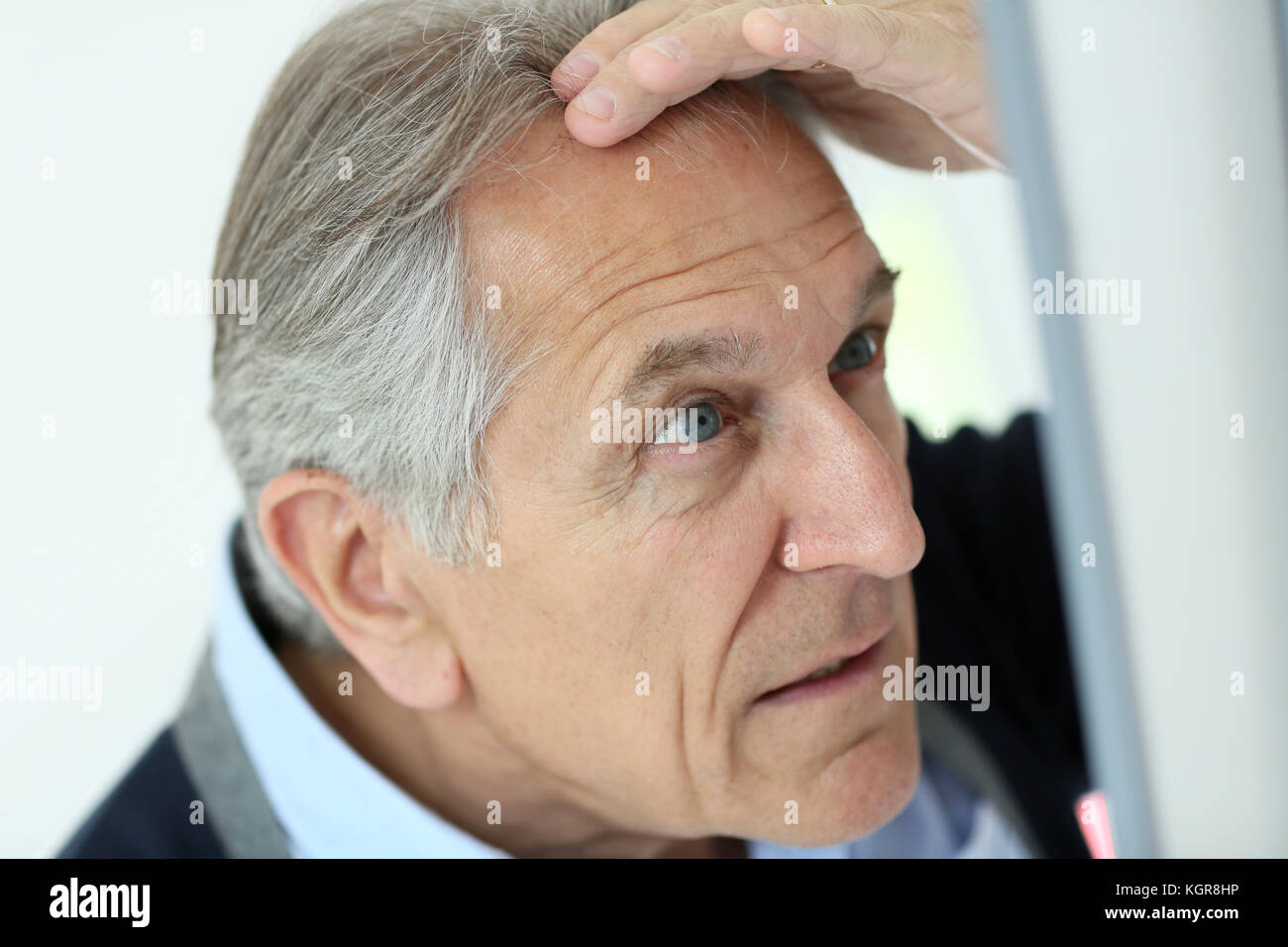 Senior man looking at hair loss in mirror Stock Photo