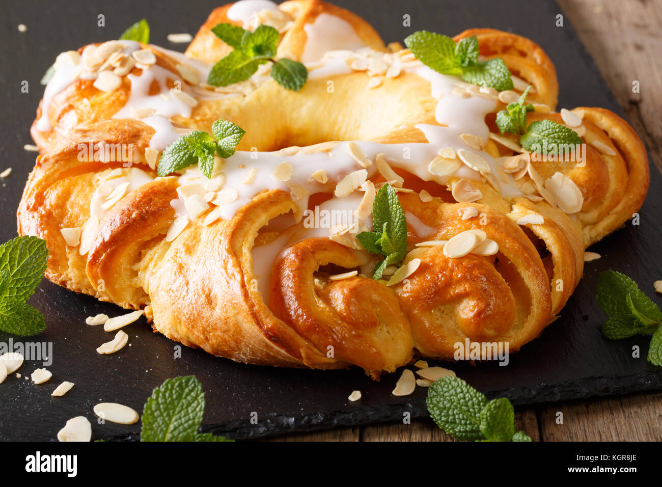 glazed round brioche cake with cheese cream and almonds close-up on the table. horizontal Stock Photo