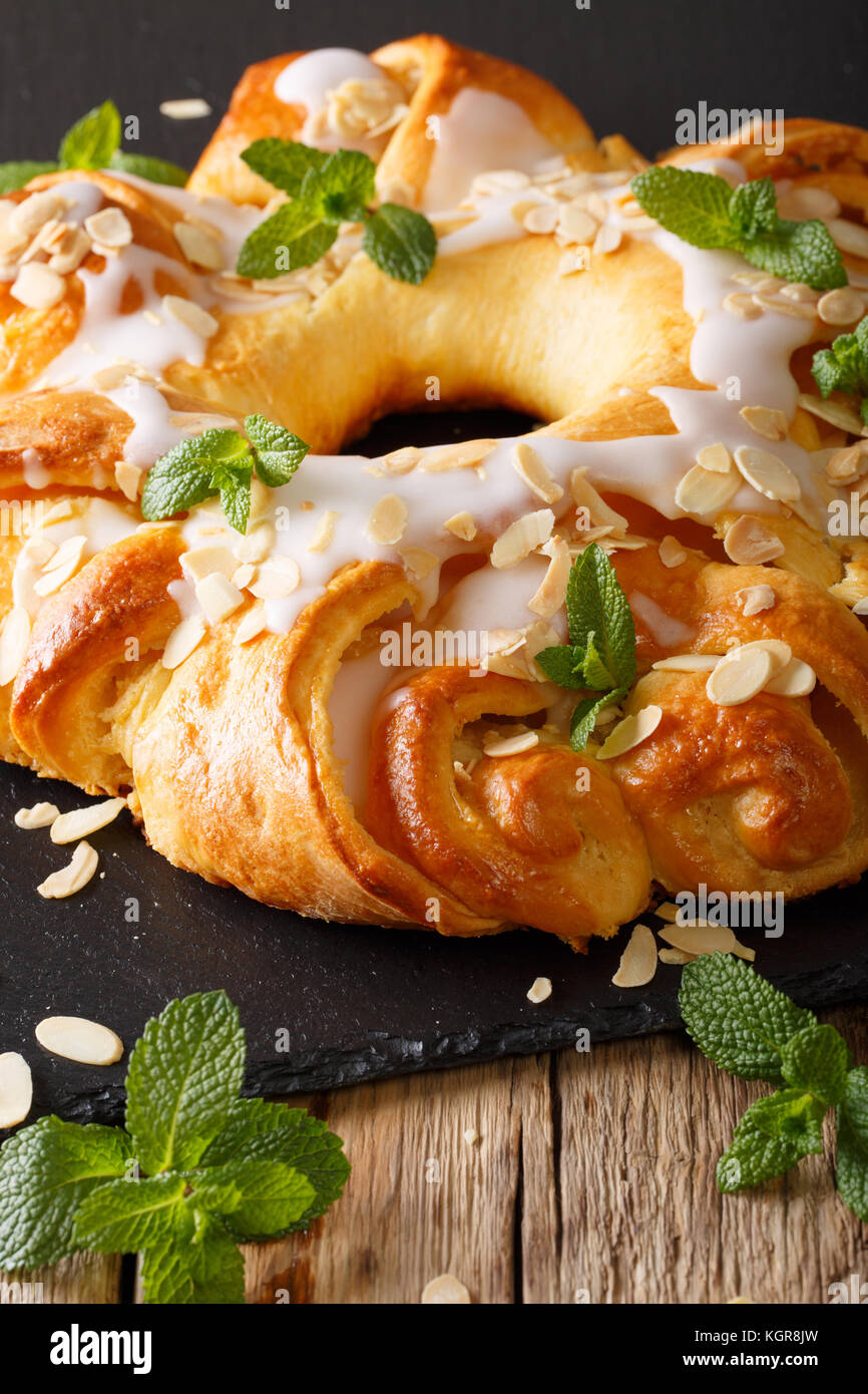 sweet brioche bun with glaze and almonds close-up on the table. vertical Stock Photo
