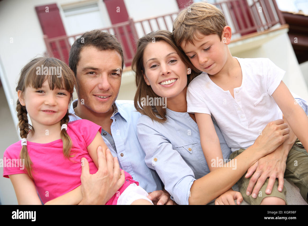 Happy family standing in front of new home Stock Photo - Alamy