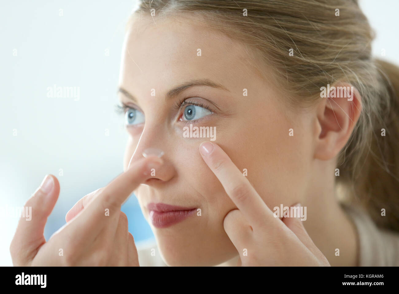 Young woman putting eye contact lense on Stock Photo