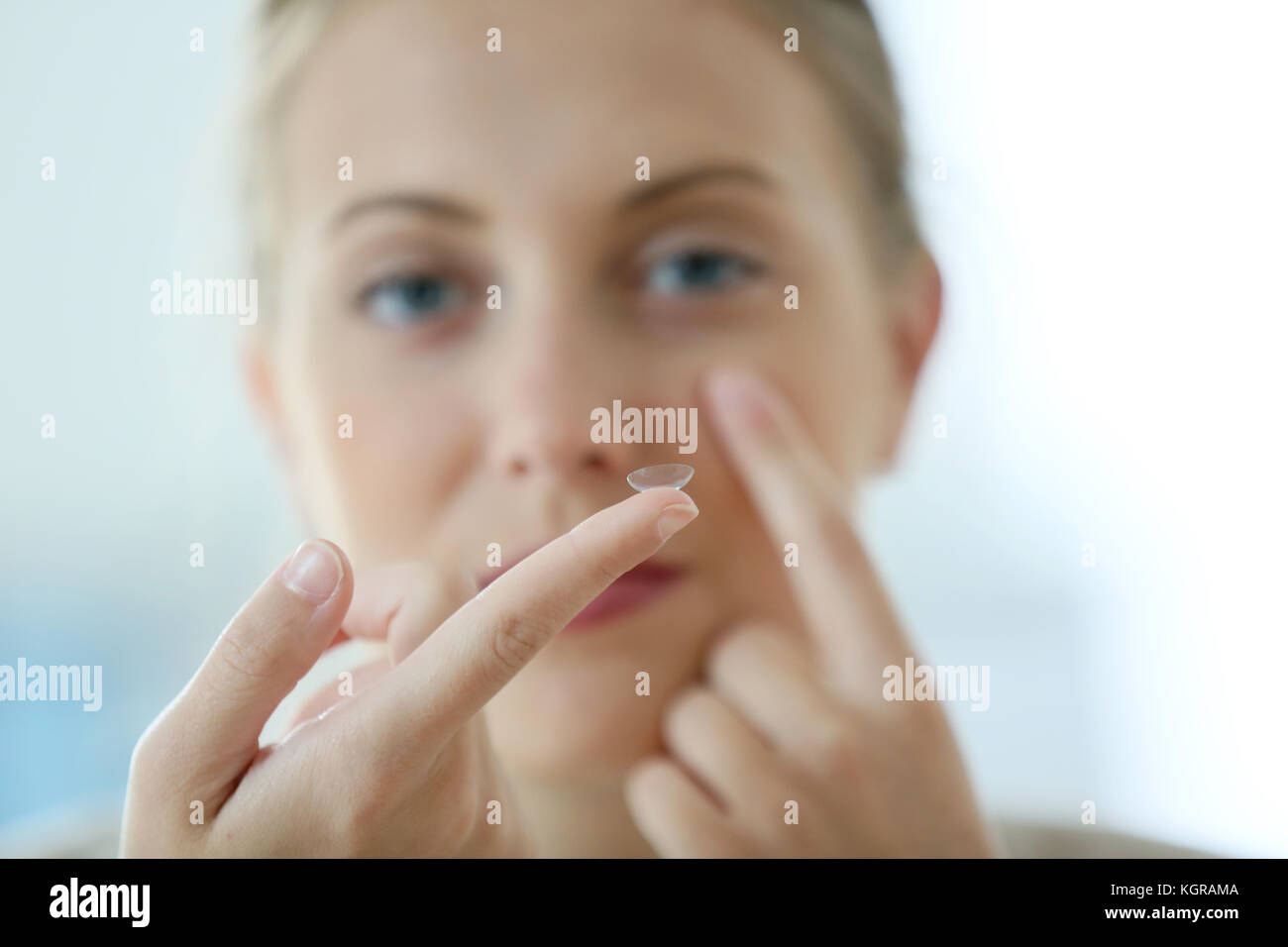 Young woman putting eye contact lense on Stock Photo