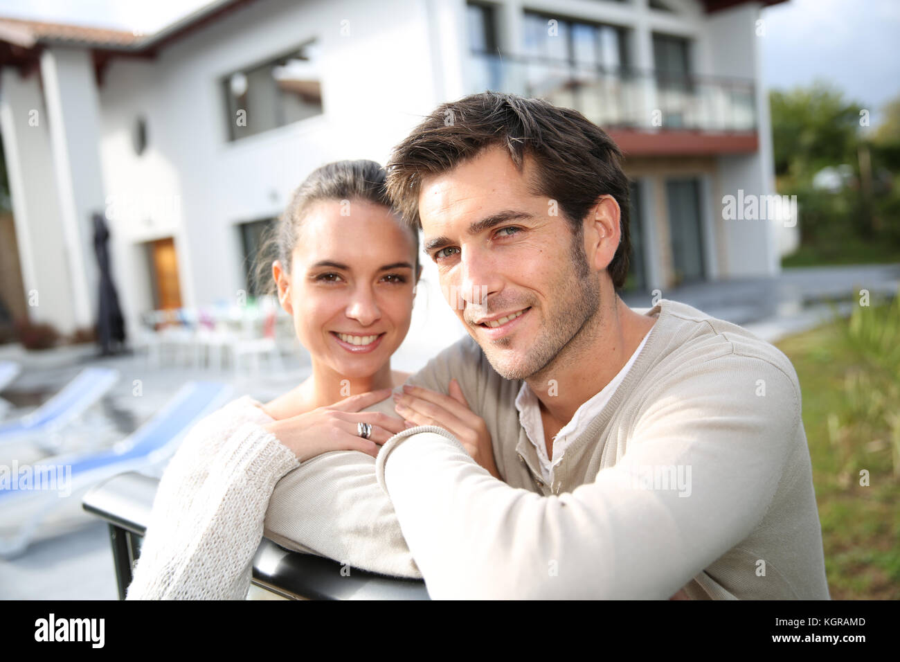 Couple standing outside in front of new home Stock Photo - Alamy