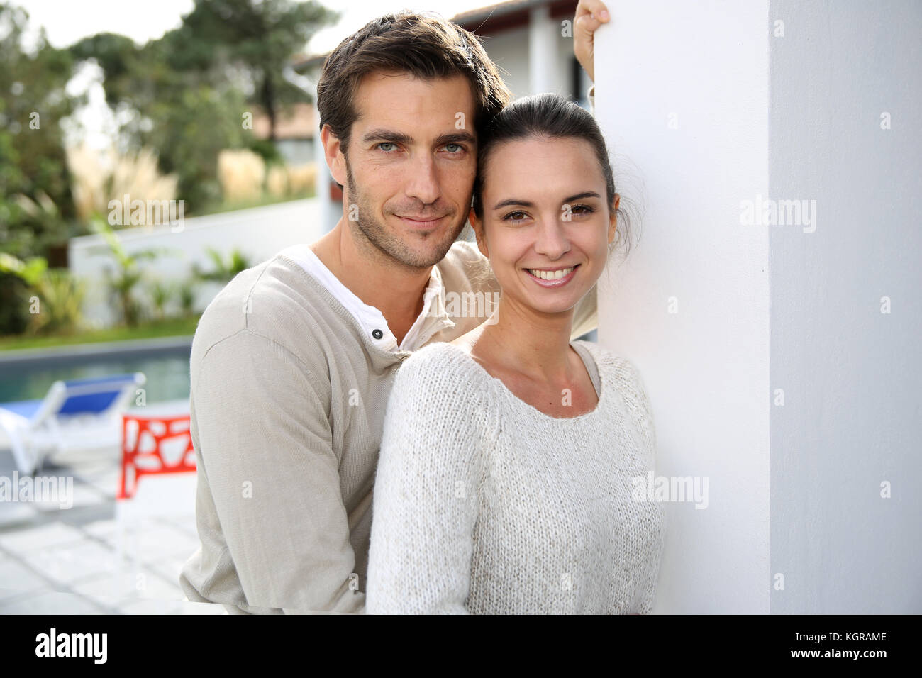 Couple standing outside in front of new home Stock Photo - Alamy