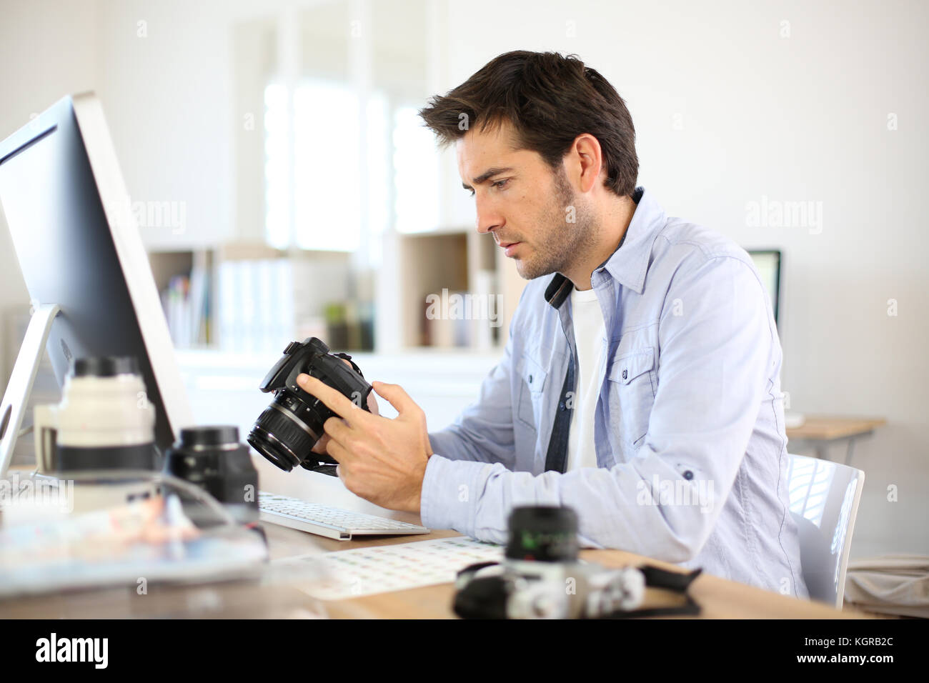 Photographer in office working on desktop computer Stock Photo