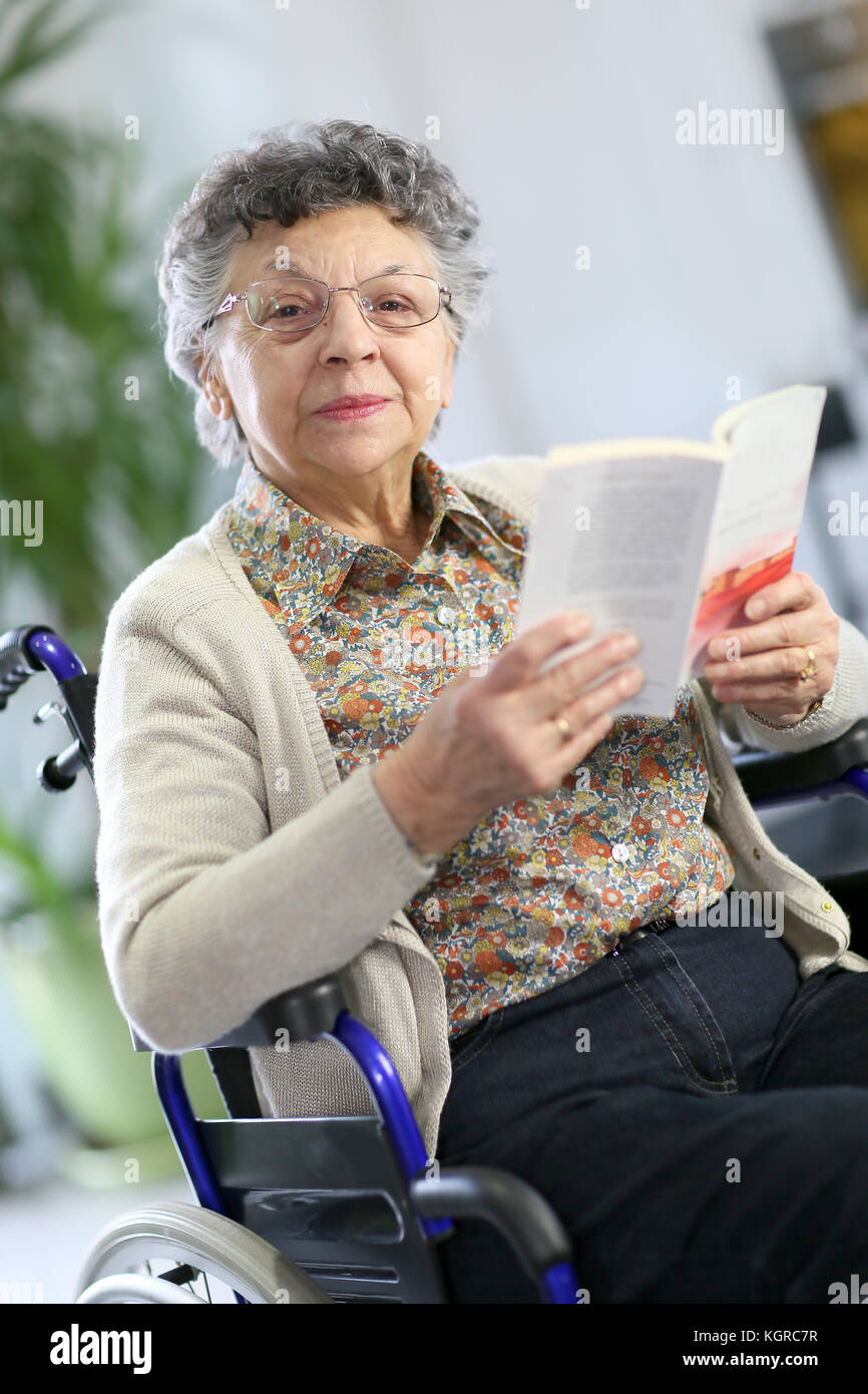 Disabled elderly woman in wheelchair reading book Stock Photo Alamy