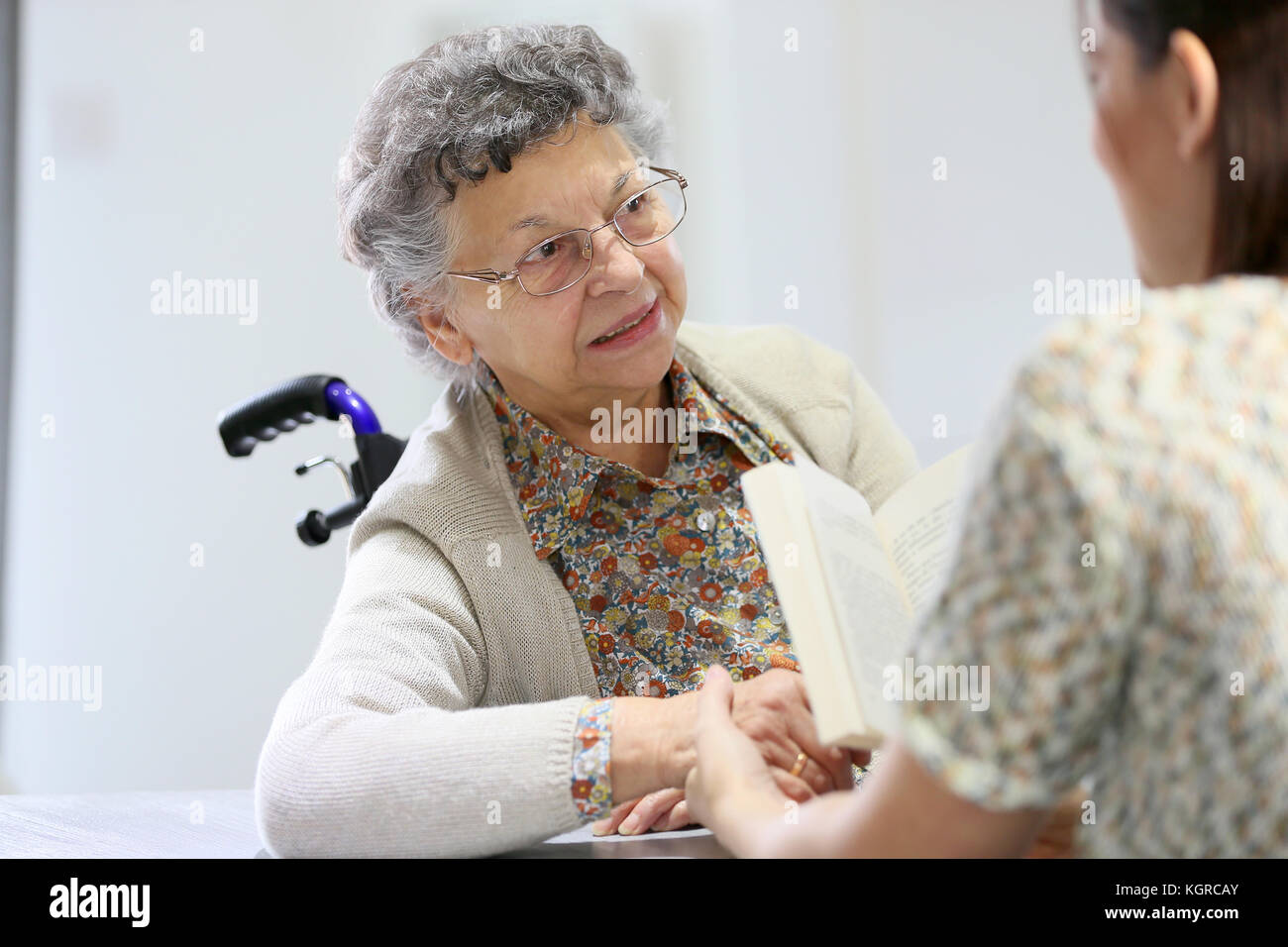 Homec arer reading book to old woman in nursing home Stock Photo Alamy