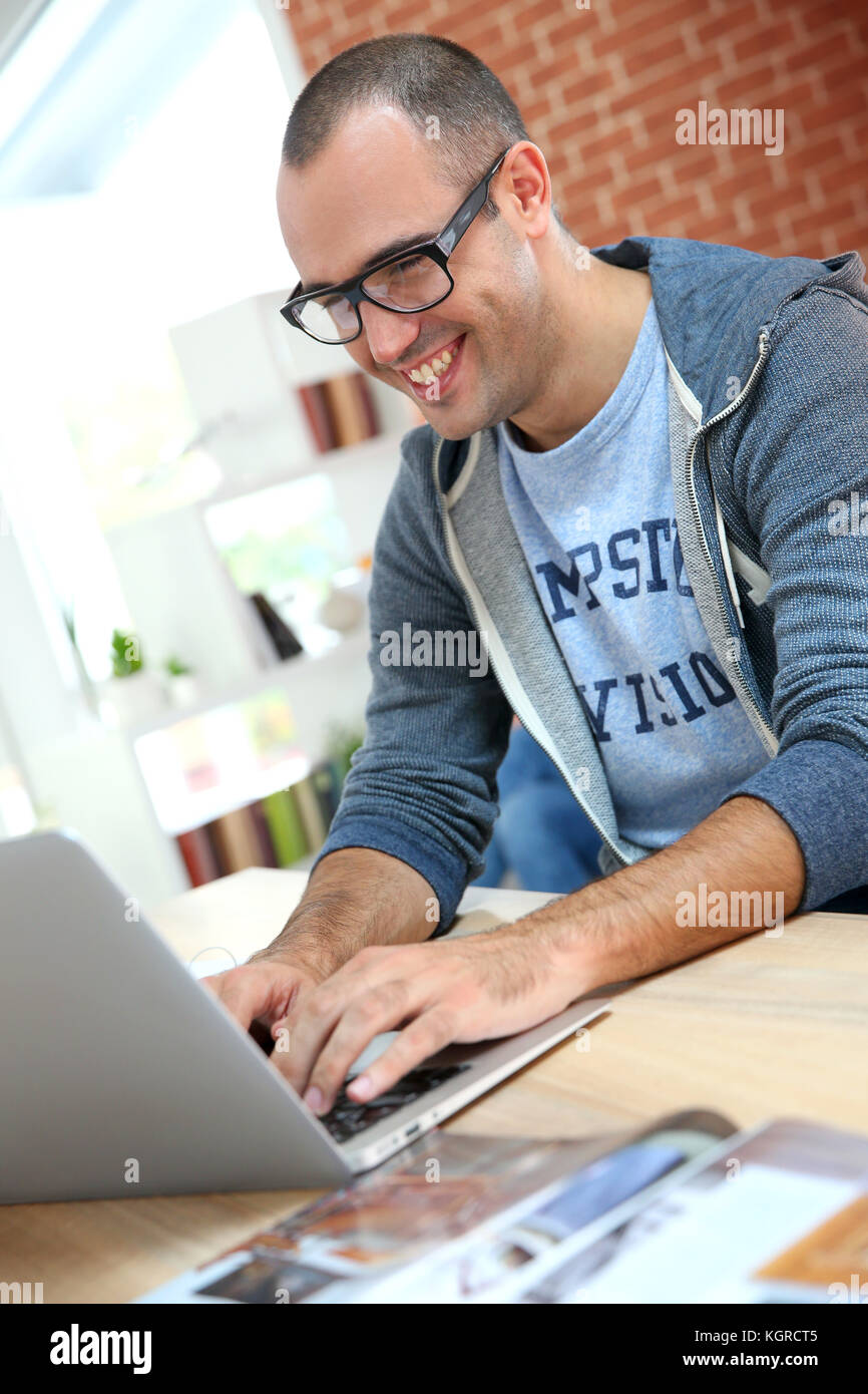Cheerful guy at home using laptop computer Stock Photo - Alamy