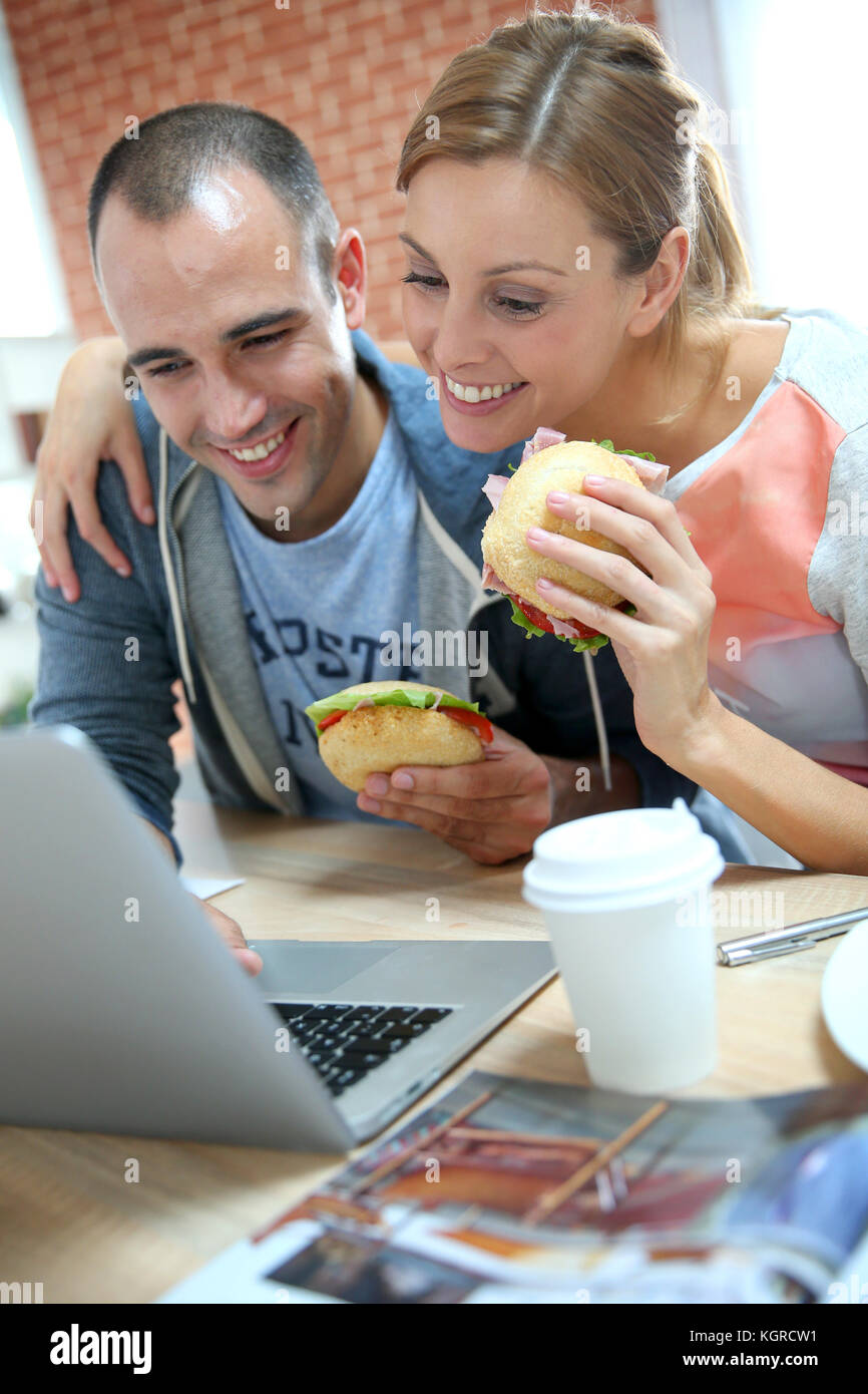 Roommates eating sandwich in front of laptop Stock Photo Alamy