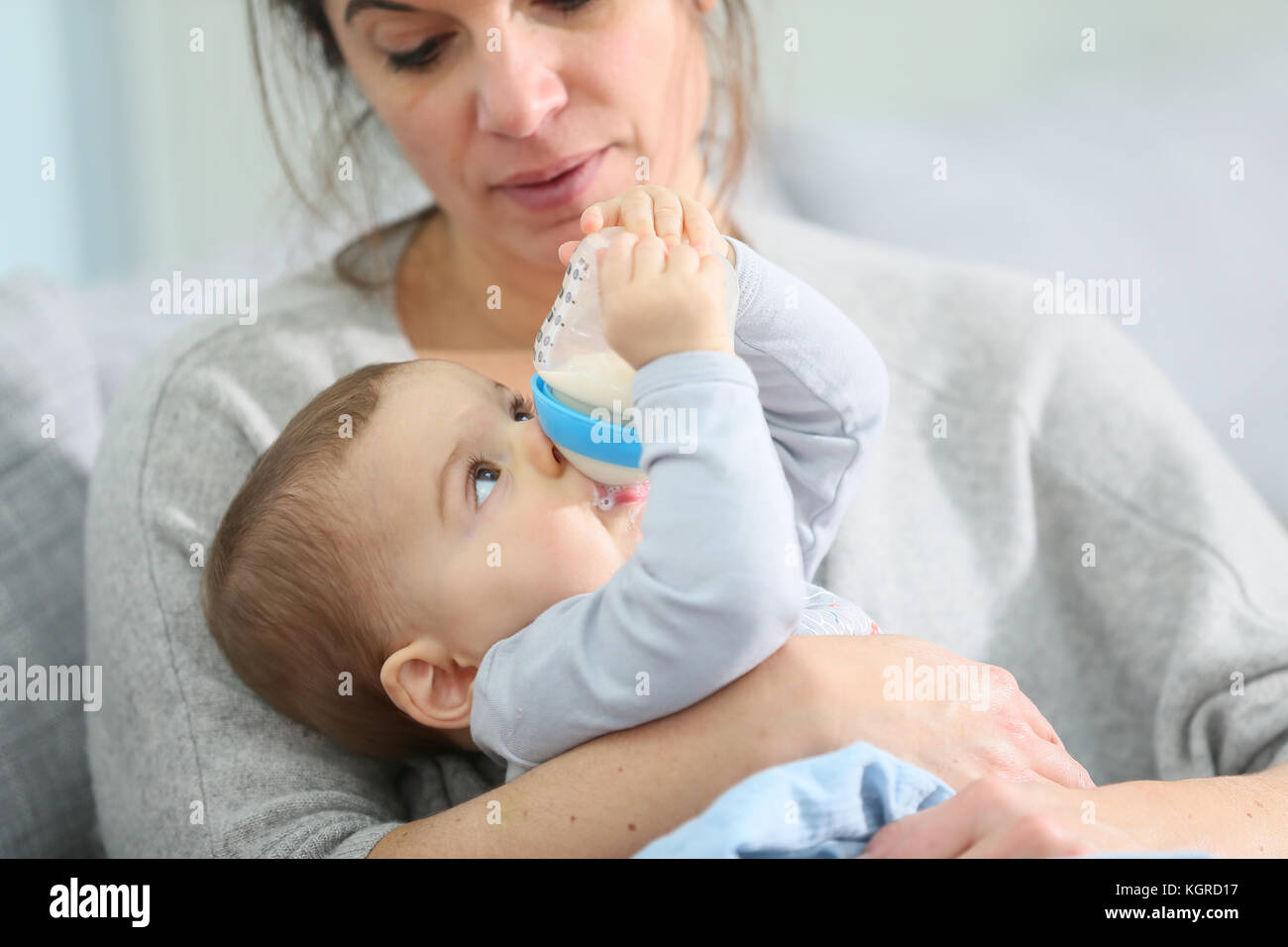Mother and baby boy holding baby bottle Stock Photo