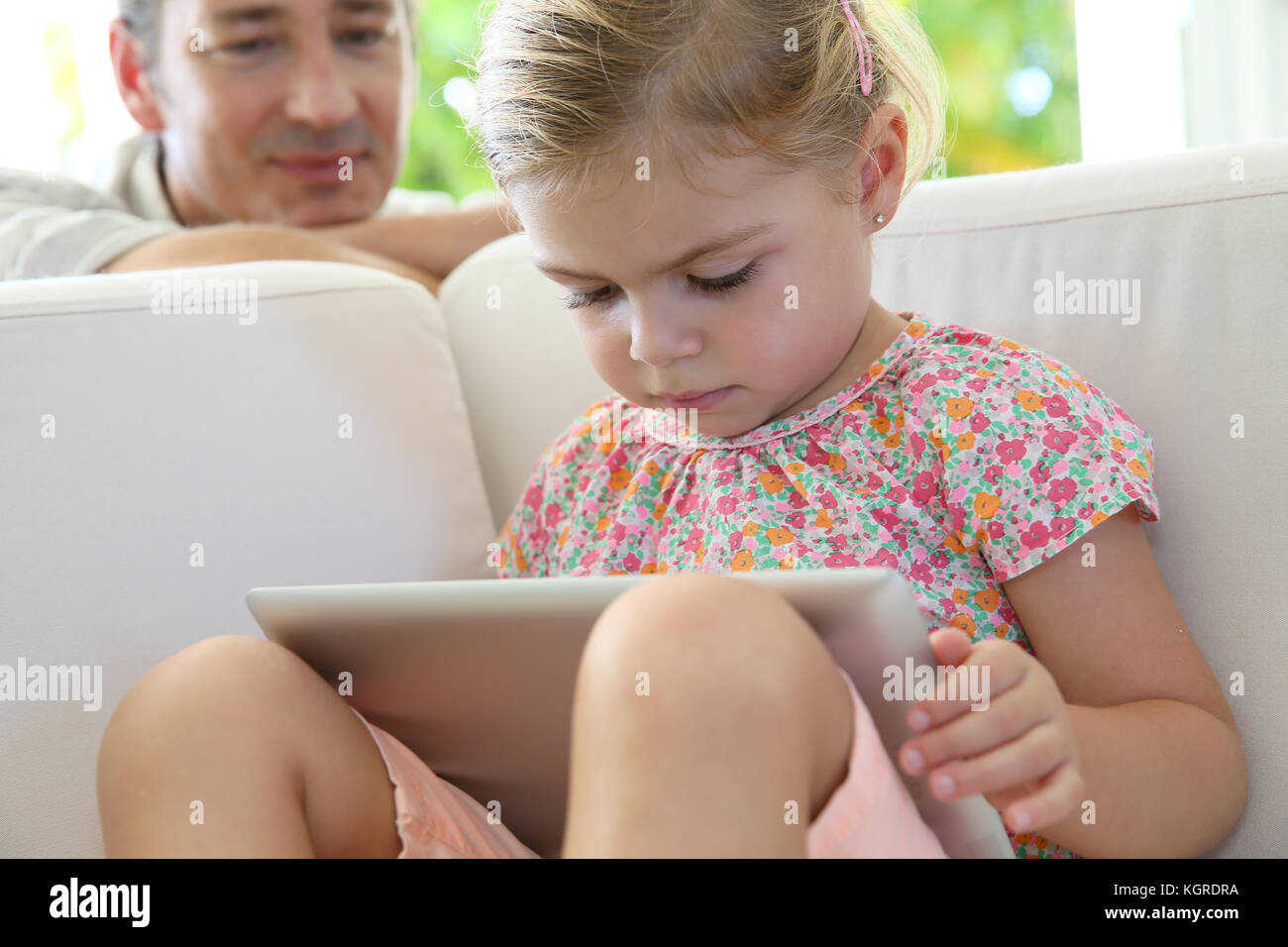 Little Girl Crying Using Tablet Little girl using tablet with care of her dad Stock Photo - Alamy