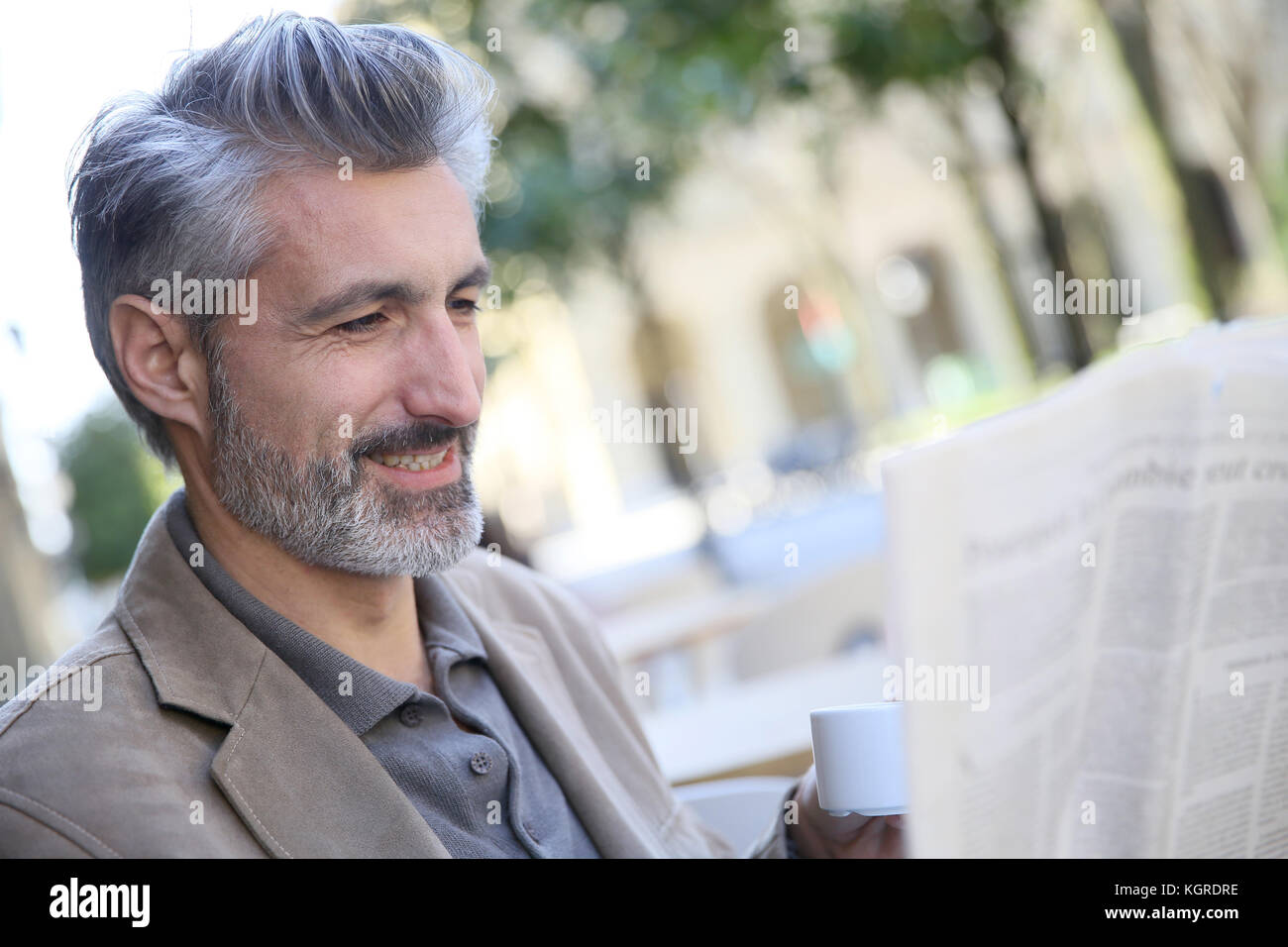 Mature man in town reading newspaper Stock Photo - Alamy