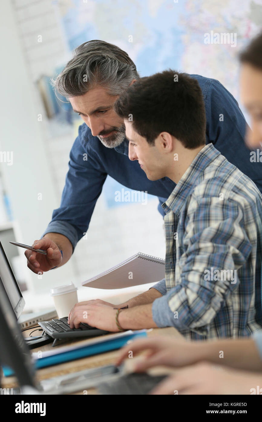 Teacher with young people in computing class Stock Photo - Alamy