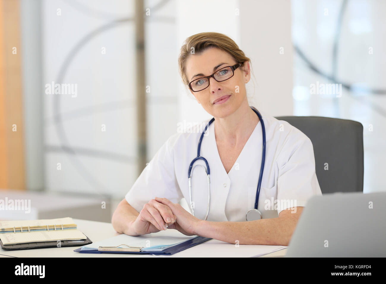 Portrait of mature nurse sitting at desk in office Stock Photo Alamy