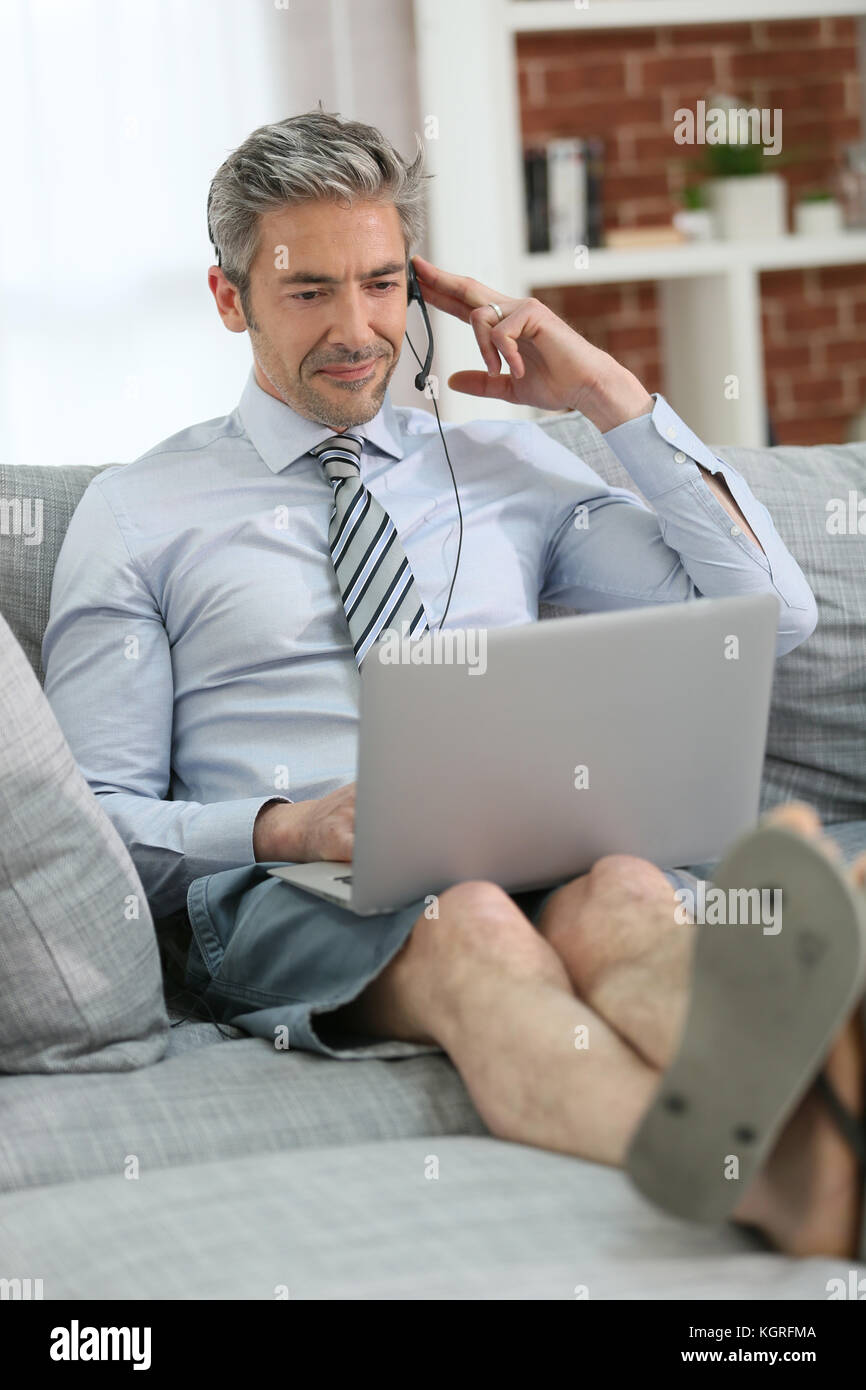 Businessman with headset working from home on couch Stock Photo Alamy