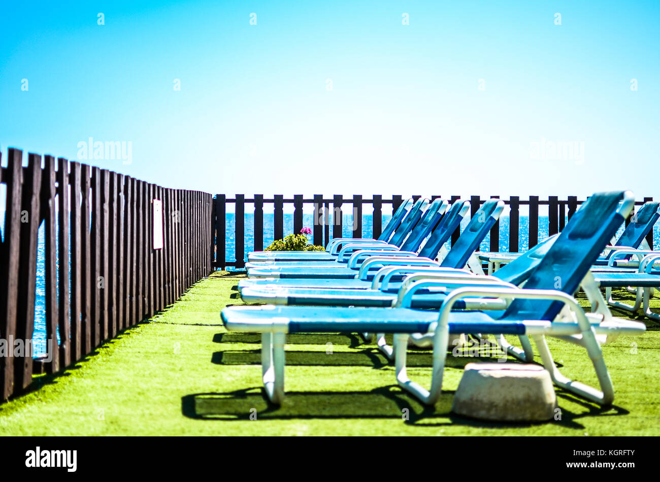 A row of sun chairs on a seaside resort overlooking the Mediterranean Sea under a clear blue sky Stock Photo