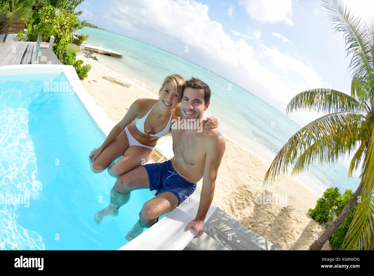 Happy young couple sitting in infinity pool Stock Photo