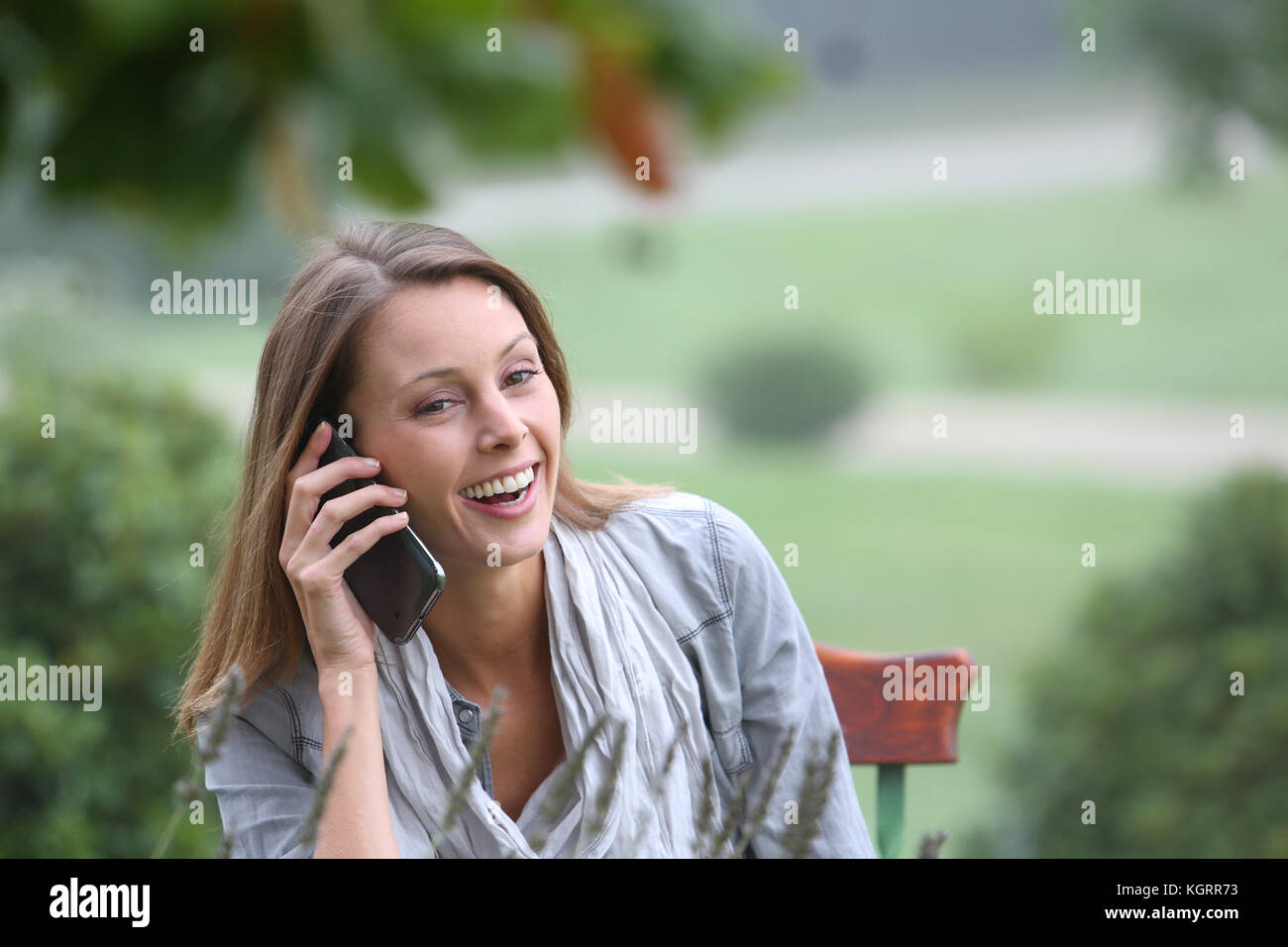 Woman in park talking on mobile phone Stock Photo - Alamy