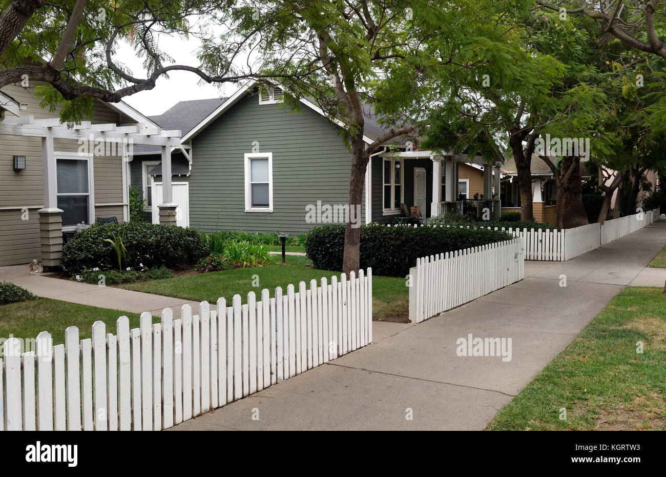 Residential neighborhood homes, picket fence, trees and sidewalk. Nobody. Stock Photo