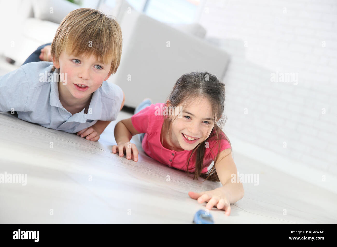 Kids playing with toy cars laying on floor Stock Photo