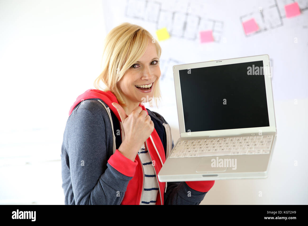 Young woman with laptop showing thumb up Stock Photo - Alamy