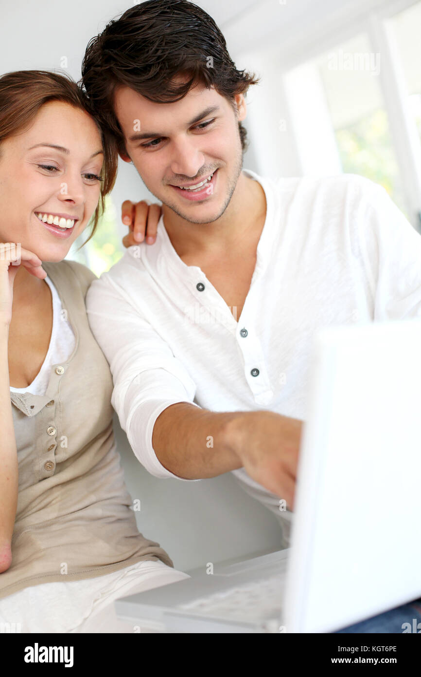 Happy young couple using laptop computer at home Stock Photo - Alamy