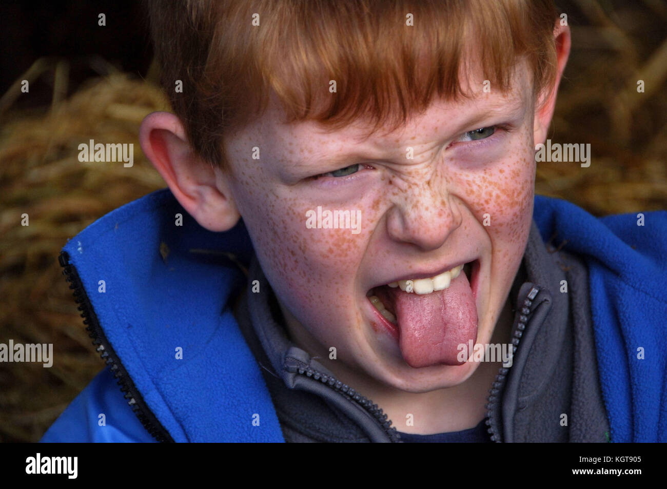 Boy sticking out his tongue which is very red hires stock photography