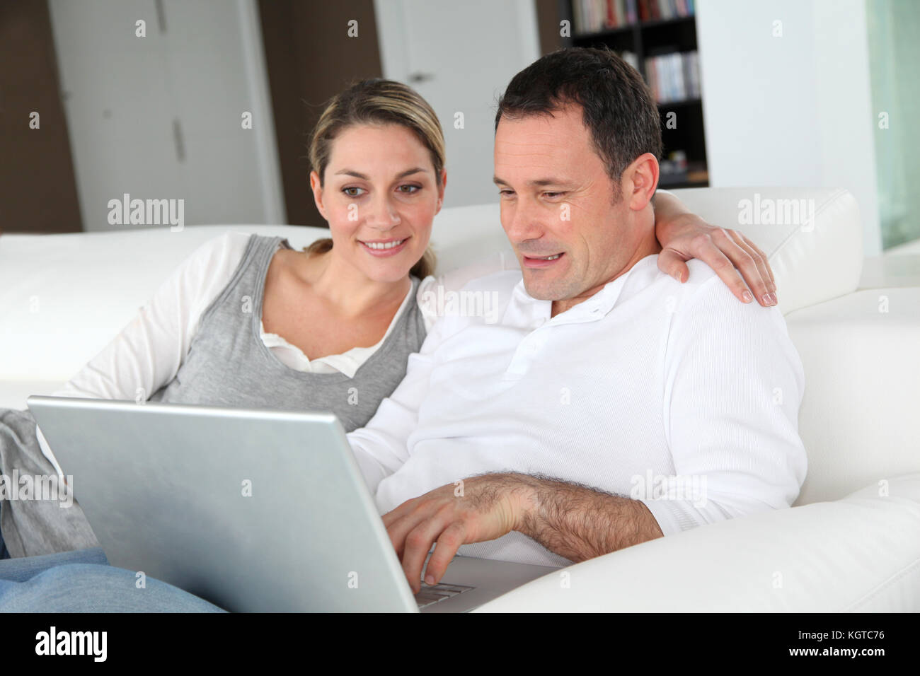 Couple relaxing in sofa with laptop computer Stock Photo - Alamy