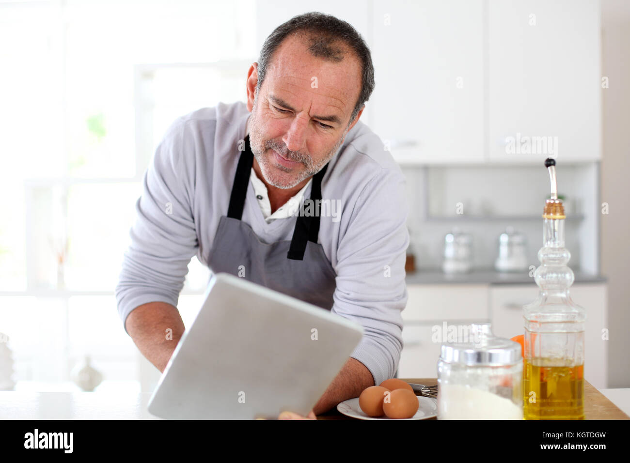 Man Using Kitchen Machine Senior man in kitchen using electronic tablet Stock Photo - Alamy