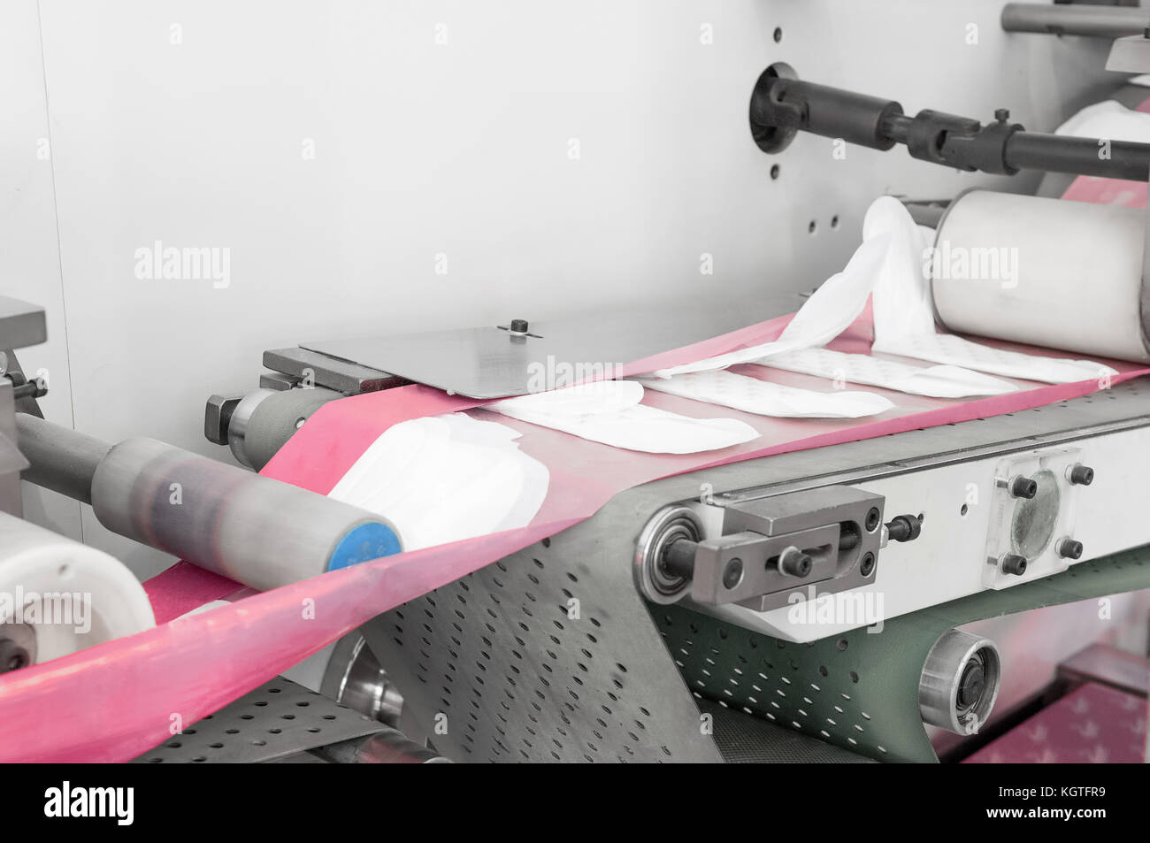 factory and equipment for the production of female sanitary napkins. women hygiene pads on a conveyor belt closeup Stock Photo