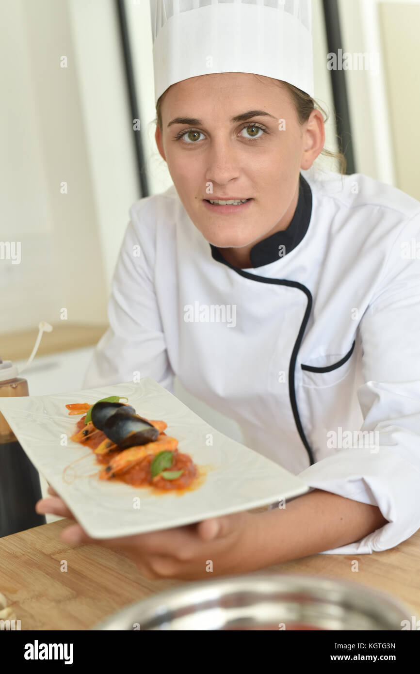 Young chef in cooking training school presenting dish Stock Photo