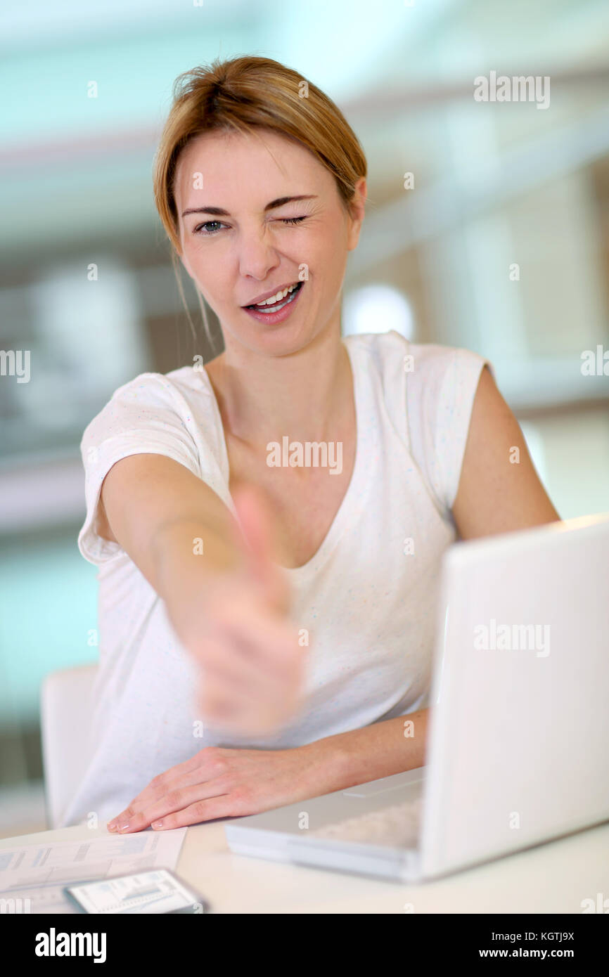 Woman in front of laptop showing thumb up Stock Photo - Alamy