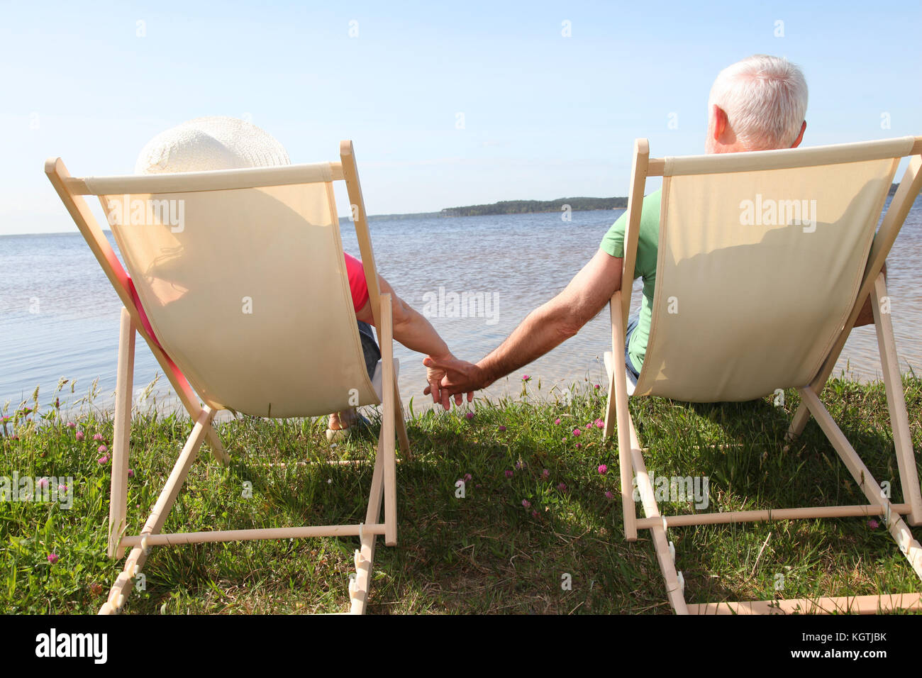 Senior couple in deck chairs in front of a lake Stock Photo - Alamy