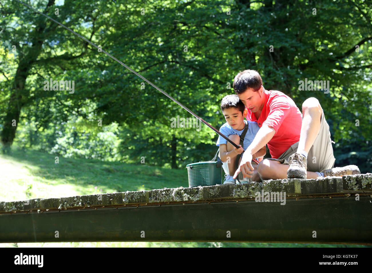 Father fishing with son on a bridge in the mountain Stock Photo