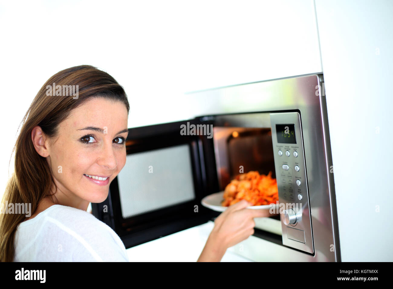 Woman putting plate in microwave oven Stock Photo
