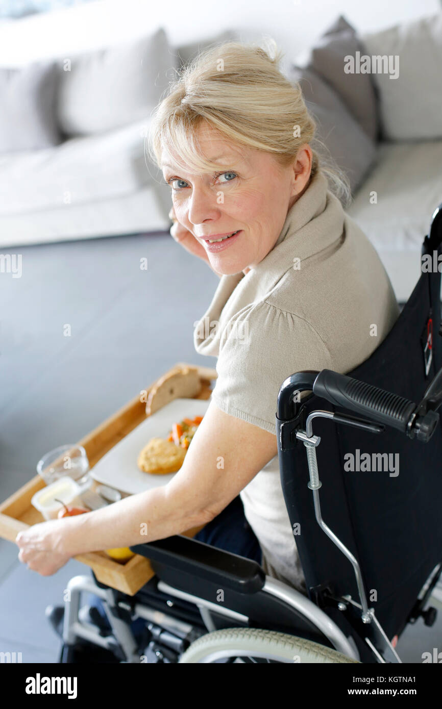 Senior woman in wheelchair holding lunch tray Stock Photo