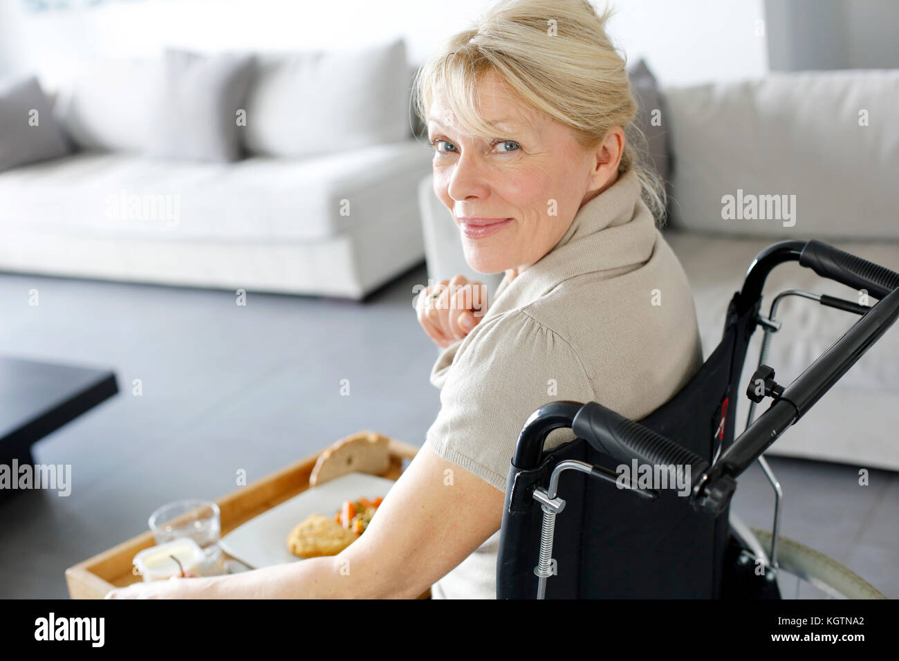 Senior woman in wheelchair holding lunch tray Stock Photo