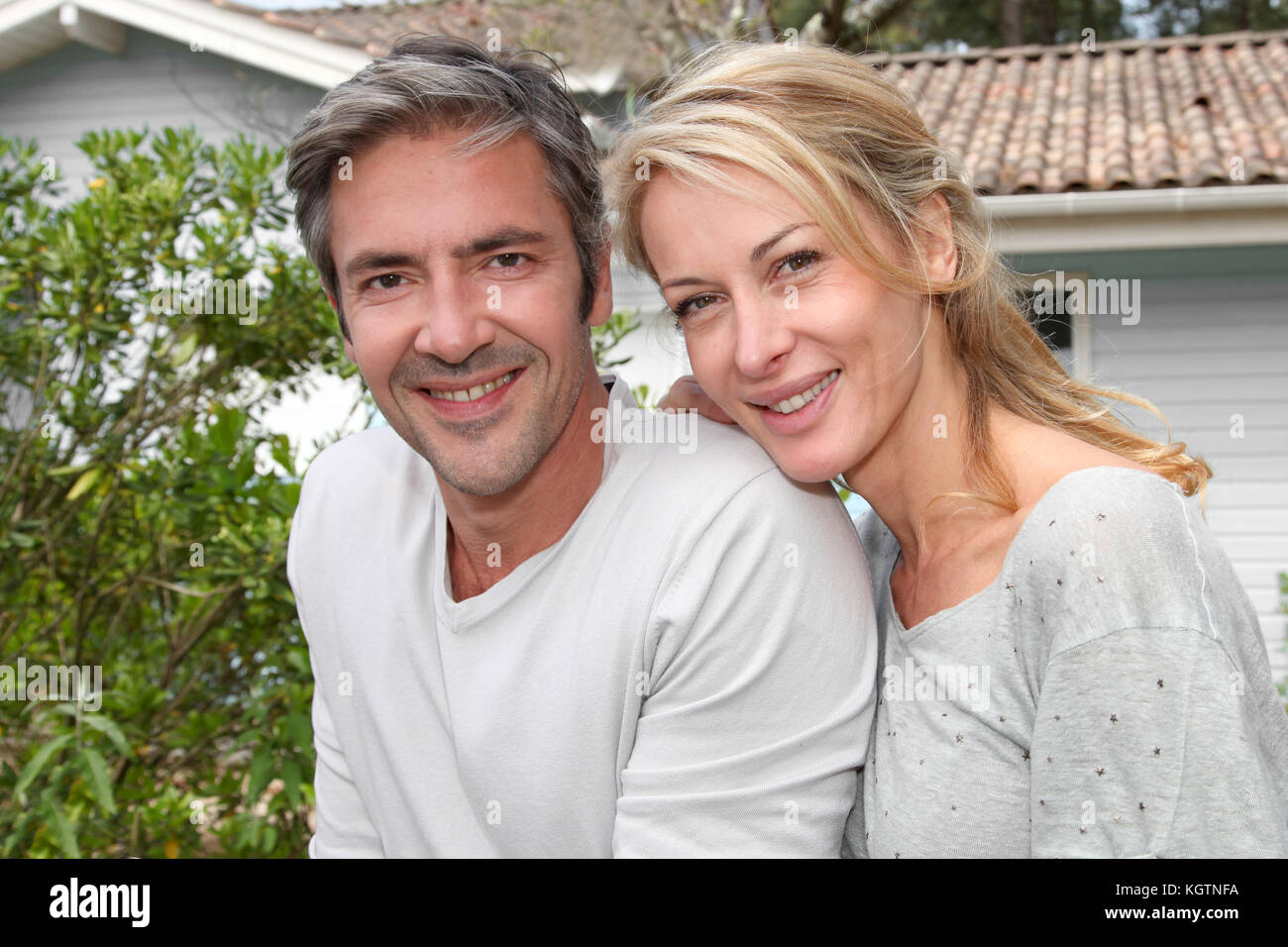 Happy couple sitting in from of their new home Stock Photo - Alamy