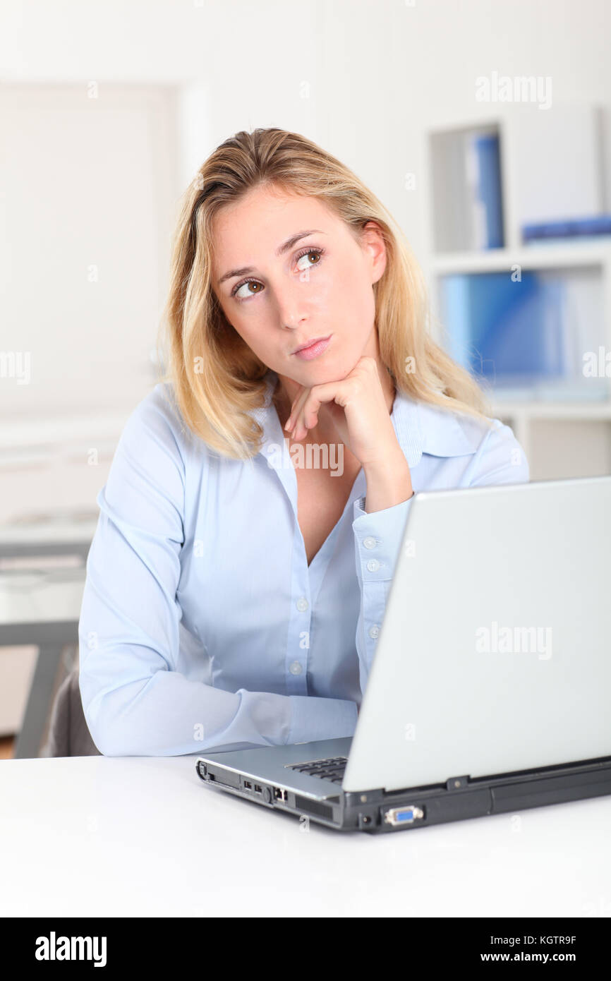 Blond woman at work with thoughtful look Stock Photo - Alamy