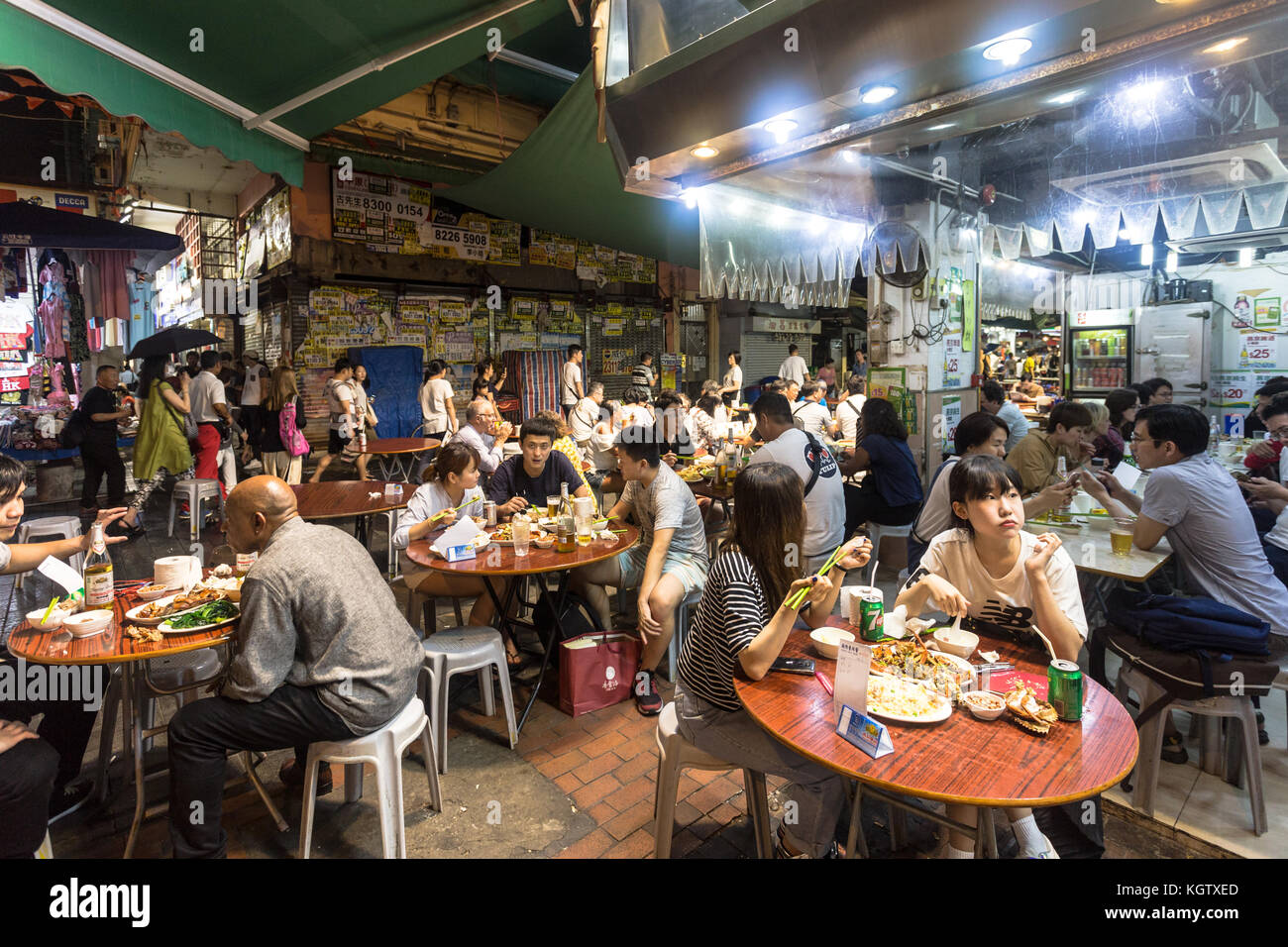 HONG KONG, CHINA - JUNE 16, 2017: Tourists and local dine in a restaurant in the streets of Kowloon near the famous Temple night market in Hong Kong. Stock Photo