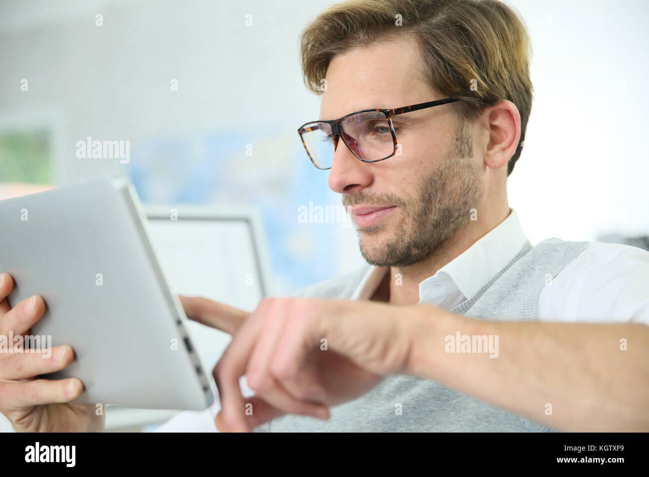 Man in office working on digital tablet, wearing eyeglasses Stock Photo