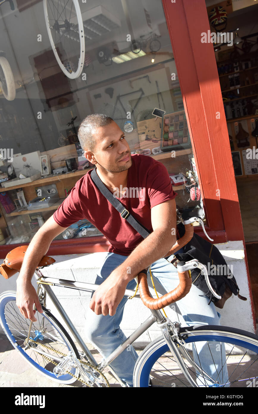 Man with bicycle waiting at shop front door Stock Photo