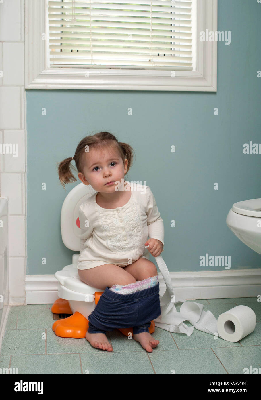 Toddler girl potty training holding toilet paper in bathroom Stock Photo -  Alamy