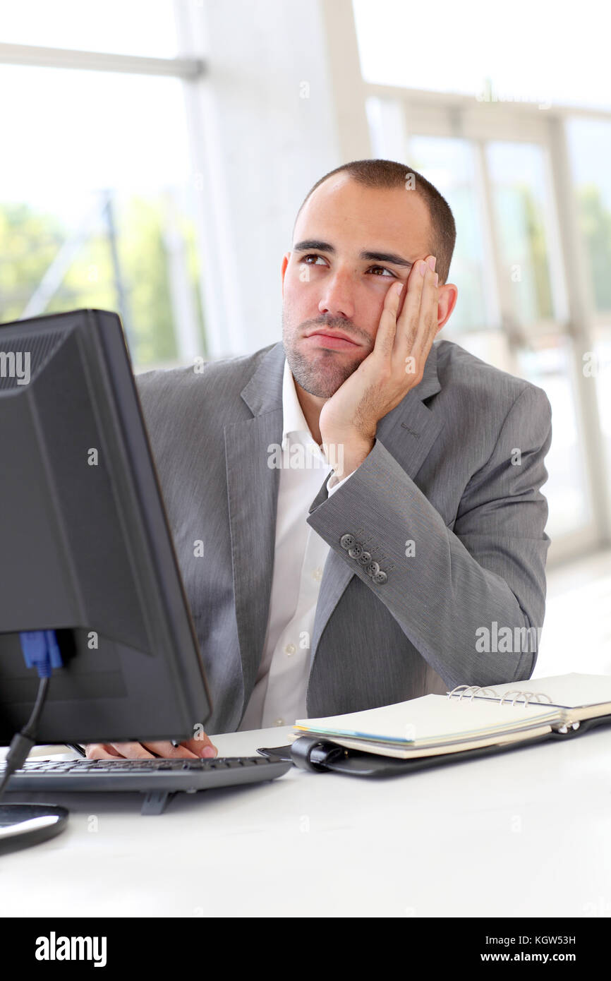 Businessman in front of desktop computer with thoughtful look Stock ...