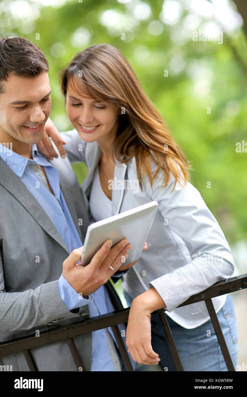 Couple standing in park with electronic tablet Stock Photo
